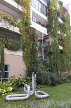 Modern façade with lush greenery and a sculpture in the front garden, Linz city centre Upper
