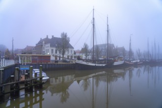Typical canal with sailing boats in the winter fog, Harlingen, Friesland, Netherlands