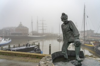 Sculpture The Tobbedanser in the foggy harbour of Harlingen, Friesland, Netherlands
