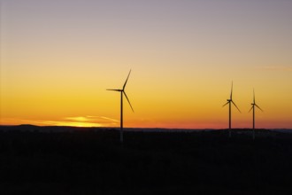 Wind turbines in front of a calm, golden sunset, near Schorndorf im Remstal, Baden-Württemberg,