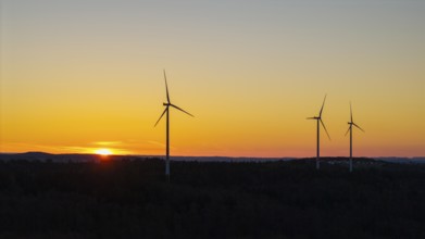 Wind turbines at dusk with an orange sky in the background, near Schorndorf im Remstal,