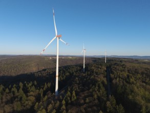 Wind turbines rise above the forest under a cloudless blue sky, near Schorndorf im Remstal,
