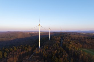 A wind farm spreads out over a wooded area under a clear sky, near Schorndorf in the Rems Valley,