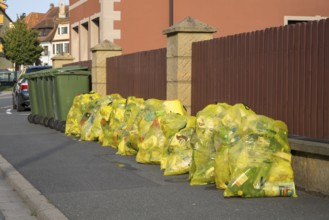 Yellow bags for plastic waste and green bins for organic waste at the roadside, waste separation,