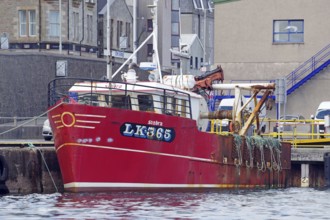 Red fishing boat in harbour against urban background with ropes on board, Lerwick, Shetland