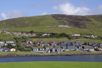 A picturesque village with colourful houses on the coast and green hills, Scalloway, Shetland