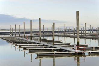 Winter day on the North Sea coast, reflection of boat moorings in the marina, Norddeich, Lower