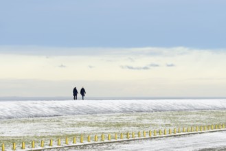North Sea coast on a winter's day, people walking over a snow-covered dyke, Norddeich, Lower