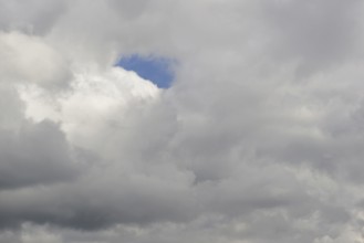 Cloud formation, blue sky shines through a gap in the closed cloud cover, North Rhine-Westphalia,
