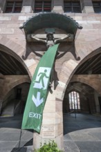 Exit sign in front of a Christ cross in the courtyard of the Heilig Geist Spital, Nuremberg, Middle
