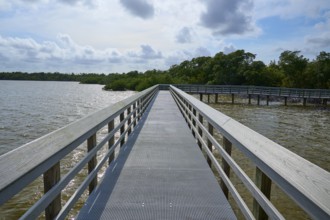 A boardwalk with railings stretches along a calm lake under a cloudy sky, West Lake View Point,