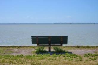 A park bench stands alone with a view of the vast, calm sea, Flamingo, Everglades National Park,