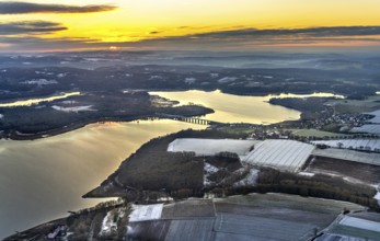 Aerial view of Lake Möhnesee in winter with snow and reflections of clouds on the water surface at