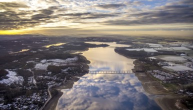 Aerial view of Lake Möhnesee in winter with snow and reflections of clouds on the water surface at
