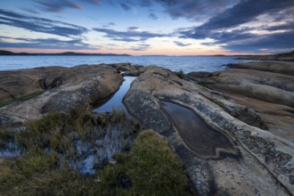 Large rocks with puddles on the coast during a sunset with clouds in the sky, Skjeberg, Sarpsborg,