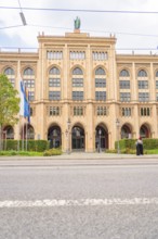 Front view of an imposing historic building with flags and green plants, Munich, Germany