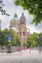 Impressive church with twin towers surrounded by trees on a cloudy day, Munich, Germany