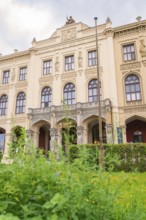 A magnificent historic building with ornate facades surrounded by lush green plants, Munich,