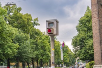 Traffic monitoring system on a busy roadside, surrounded by green trees, Munich, Germany