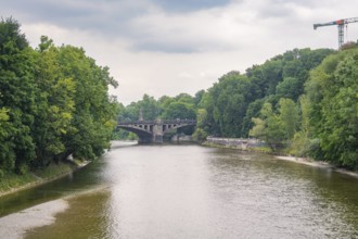 River view with a stone bridge in the background, surrounded by dense forests and a peaceful