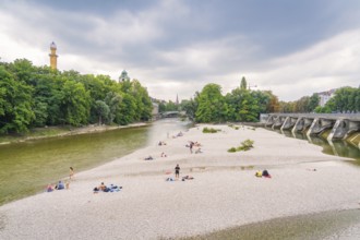 River landscape with island and bridge, surrounded by trees. People enjoying their free time on the