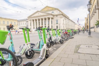 E-scooters and bicycles in front of a majestic building in the city of Munich, Munich, Germany