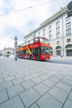 A red double-decker bus for city tours in front of historic buildings in Munich, Munich, Germany