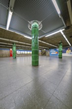 Spacious underground station with striking green columns in a simple atmosphere, Munich, Germany
