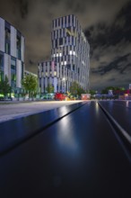 Modern building at night with strong lighting and cloudy sky, urban and stylish, Munich, Germany