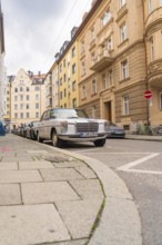 Classic Mercedes on a cobbled city street with parked cars and old buildings, Munich, Germany