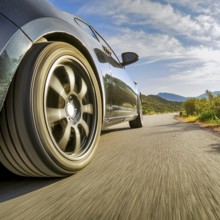 Low angle scenery showing a driving sports car on a street in sunny ambiance, AI generated image