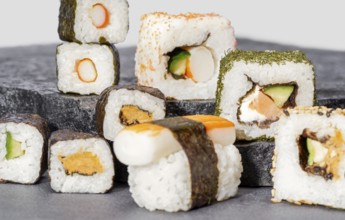 Various sushi dishes on dark grey stone surface