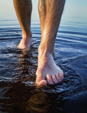 AI generated image showing a pair of male feet walking over water surface