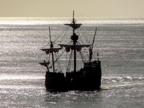 Silhouette of a historic sailing ship near Madeira in glittering water ambiance