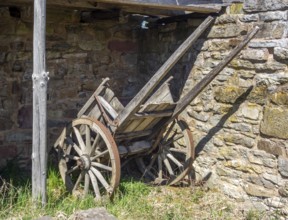 Medieval wooden cart at a stone wall in sunny ambiance