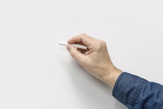 Male hand with white crayon in light back