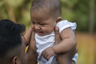 Baby laughing joyfully as they are lifted up outdoors-Dhaka, Bangladesh