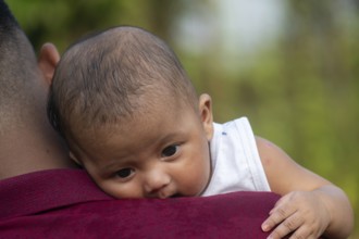 Baby relaxes on a man's shoulder in a calm outdoor setting-Dhaka, Bangladesh