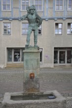 Wood carrier by Bernhard Frydag, 1914, male figure carrying basket with wood on his back, symbol
