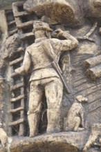 Relief on the market fountain, sculpture, hunter with shotgun watching with binoculars, hunting,