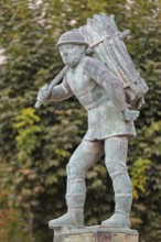 Wood carrier by Bernhard Frydag, 1914, male figure carrying basket with wood on his back, symbol