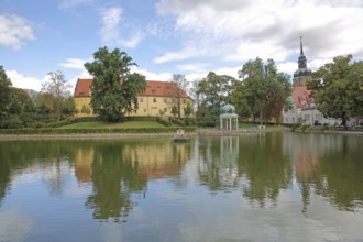 Castle and round pavilion at the spa park pond with church tower of the town church, reflection,