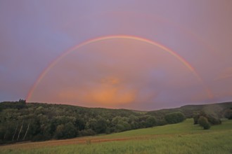 Half-round rainbow with forest and fields, landscape, light mood, nature photography,