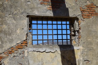 Barred window with shadows on old, rustic brick walls, Old silk factory, Military prison of the