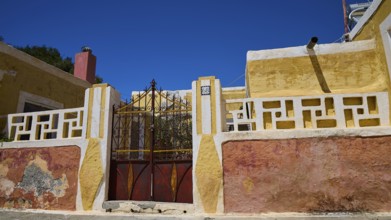 A yellow rustic building with a metallic Tor tor under a blue sky, Kattavia village, southern tip