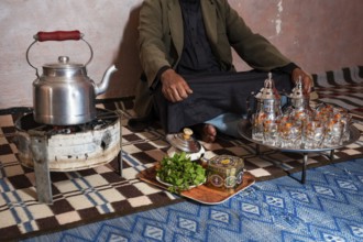 Moroccan man in front of the tea set with the kettle and glasses