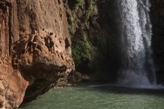 OUZOUD, MOROCCO - OCTOBER 5, 2024: Two Moroccan boys climbs the rock before jump from into the