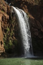 Relaxed woman floats on his back under beautiful Ouzoud waterffall in Morocco