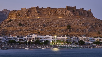 Feraklos fortress, Old castle at dusk with illuminated town and calm sea below, bay, Charaki,
