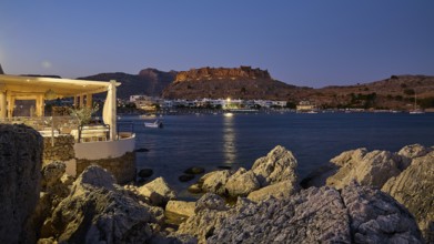 Argo restaurant, Feraklos fortress, night view of a castle above a quietly lit coastal town by the